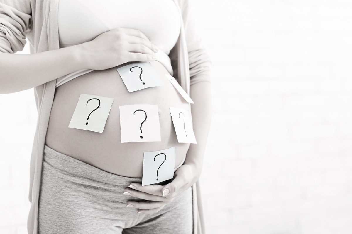 Femme enceinte se tenant le ventre avec des points d'interrogations